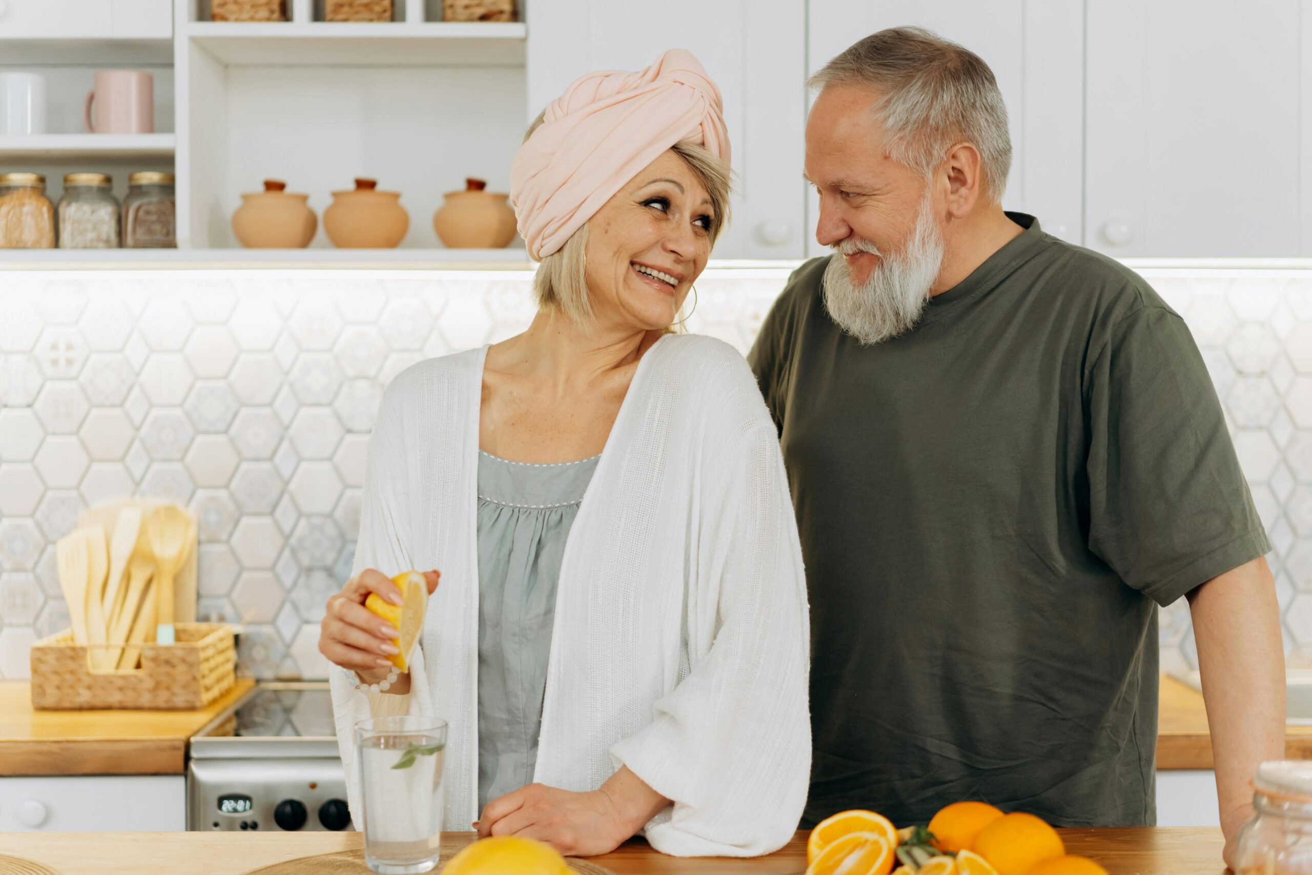 Smiling senior couple making fresh juice in the cozy kitchen setting.